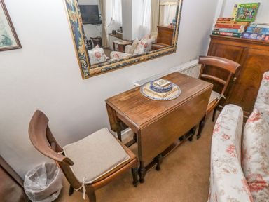 A small wooden table with two chairs and a mirror above it in a living room at Newbury Cottage in Bourton-On-The-Water