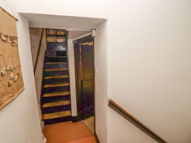 A narrow staircase with wooden steps and a handrail next to a door in a hallway at Newbury Cottage in Bourton-On-The-Water