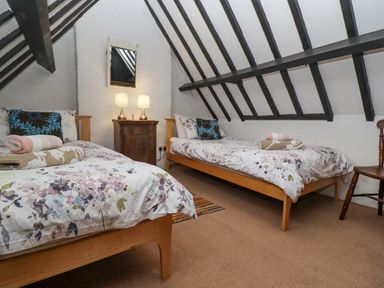 A bedroom with two single beds wooden chair and cabinet with lamps at Newbury Cottage in Bourton-On-The-Water