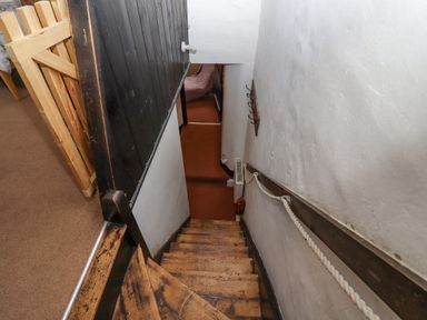 A wooden staircase with rope handrail leading down to a carpeted hallway at Newbury Cottage in Bourton-On-The-Water