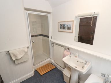 A bathroom with a shower enclosure sink mirror and towel racks at Newbury Cottage in Bourton-On-The-Water