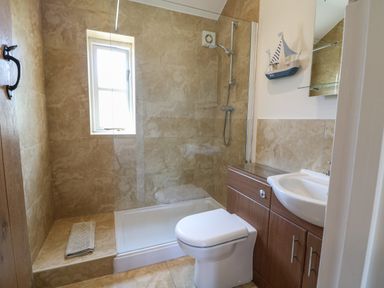 A bathroom with a shower area toilet and sink at Saddlebacks Barn Burford