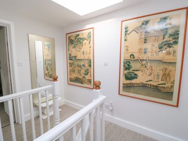 A hallway with wall art and a mirror at Fairview Cottage in Milton-Under-Wychwood
