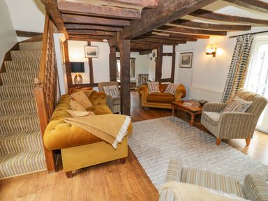 A living room with sofas and a staircase at Elmhurst Cottage in Lower Quinton