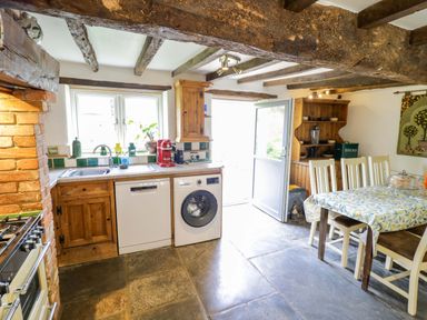 A kitchen with a sink, dishwasher, and table at Elmhurst Cottage in Lower Quinton
