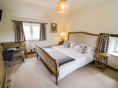 A bedroom with a bed and desk at Elmhurst Cottage in Lower Quinton
