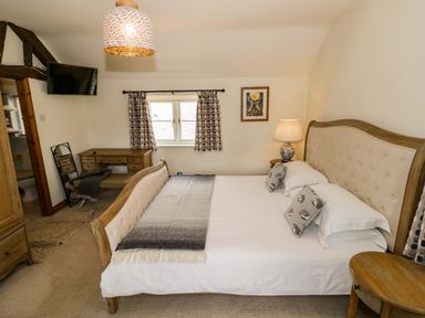 A bedroom with a bed and a desk at Elmhurst Cottage in Lower Quinton