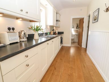 A kitchen with white cabinets black countertop wooden floor and stainless steel appliances at Ewecub Barn in Burford