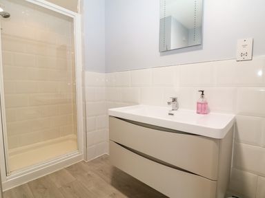 A bathroom with a shower enclosure and a sink with a mirror and soap dispenser at South Hill Farmhouse in Stow-On-The-Wold