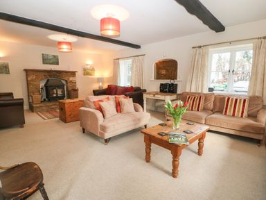 A living room with sofas a wooden coffee table and a stone fireplace at South Hill Farmhouse in Stow-On-The-Wold