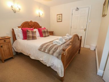 A bedroom with a wooden bed with pillows and rolled towels at South Hill Farmhouse in Stow On The Wold
