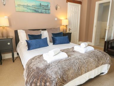 A bedroom with a bed with pillows and folded towels on a fur blanket at South Hill Farmhouse in Stow-On-The-Wold