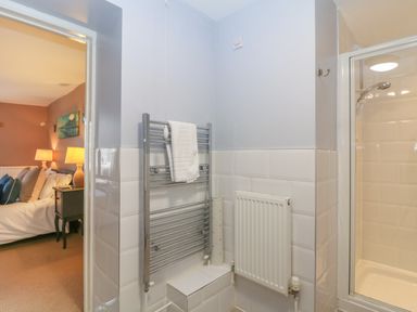 A bathroom with a chrome towel rack radiator a white radiator and a shower cubicle with a glass door at South Hill Farmhouse in Stow-On-The-Wold