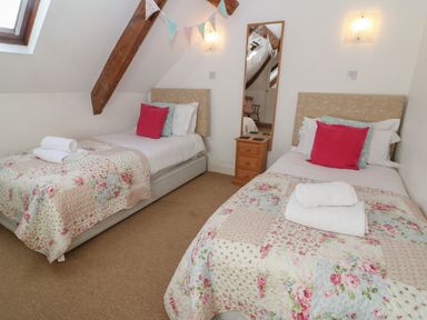 A bedroom with two single beds and floral quilts at South Hill Farmhouse in Stow-On-The-Wold