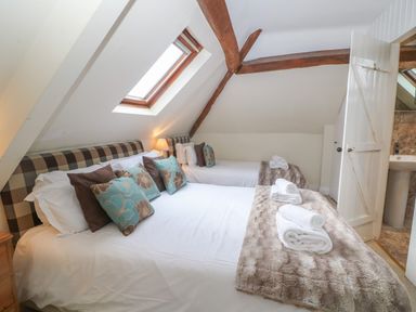 A bedroom with two beds under a sloped ceiling with wooden beams and a skylight at South Hill Farmhouse in Stow-On-The-Wold