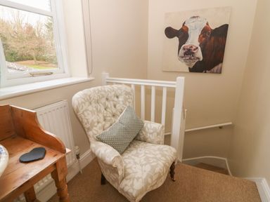 A chair with a cushion next to a wooden desk near a window and staircase at South Hill Farmhouse in Stow-On-The-Wold