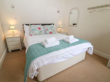 A bedroom with a double bed with floral pillows and two bedside tables with lamps at South Hill Farmhouse in Stow-On-The-Wold