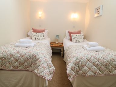 A bedroom with two single beds and a wooden side table with a lamp at South Hill Farmhouse in Stow-On-The-Wold