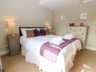 A bedroom with a double bed bedside tables lamps and a chest of drawers at South Hill Farmhouse in Stow-On-The-Wold