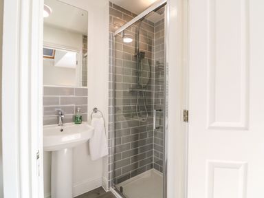 A bathroom with a pedestal sink a mirror a towel ring with a towel and a glass door shower at South Hill Farmhouse in Stow-On-The-Wold