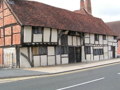 A historic timber framed building with white walls and dark wood beams on a street corner at One Masons Court in Stratford upon Avon