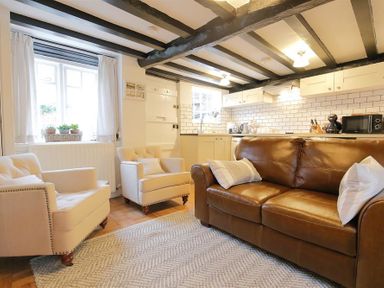 A living room with two armchairs a leather sofa and a kitchen in the background at One Masons Court in Stratford upon Avon