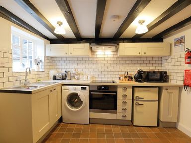 A kitchen with a washing machine oven fridge microwave and sink at One Masons Court in Stratford upon Avon