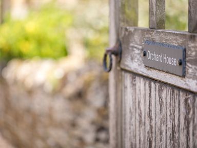 A close up of a weathered wooden gate with a sign that says Orchard House at Orchard House in Stow-On-The-Wold