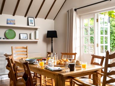 A dining room with a wooden table and chairs and breakfast items on the table at Orchard House in Stow-On-The-Wold