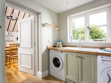 A laundry room with a washing machine dryer sink and window at Orchard House in Stow-On-The-Wold