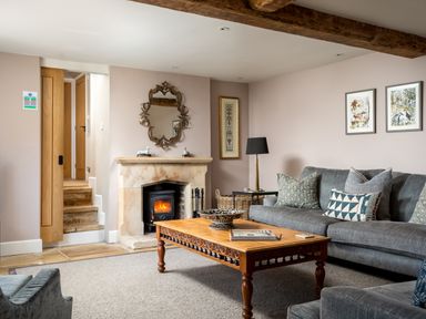 A living room with a fireplace wooden coffee table gray sofa and framed pictures at Orchard House in Stow-On-The-Wold