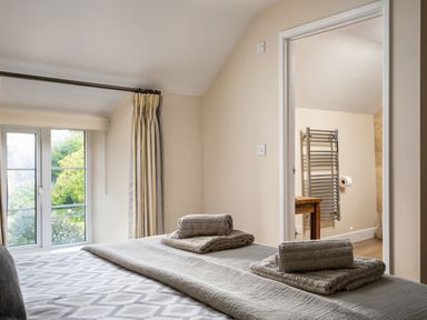 A bedroom with a bed made with folded towels and a window with curtains at Orchard House in Stow-On-The-Wold