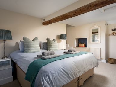 A bedroom with a double bed two lamps a mirror and wicker baskets at Orchard House in Stow-On-The-Wold