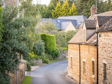 A narrow road lined with stone houses and trees at Orchard House in Stow On The Wold
