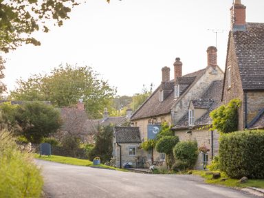 A street with stone cottages and greenery in a rural area