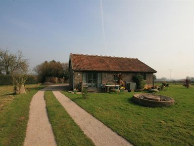 A small stone house with a tiled roof and a gravel driveway in a grassy area at The Piggery in Lydney