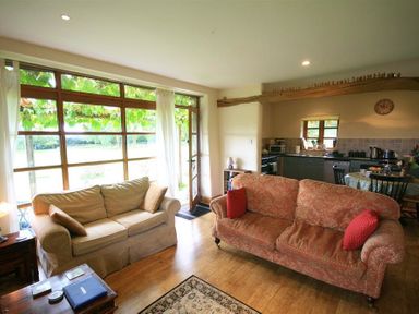 A living room with two sofas near large windows and an open kitchen area at The Piggery in Lydney