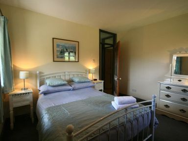 A bedroom with a double bed bedside tables lamps and a dresser with a mirror at The Piggery in Lydney