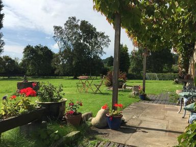 A garden with flower pots tables chairs and a soccer goal on the grass at The Piggery in Lydney