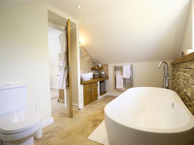 A bathroom with a bathtub toilet sink and towels at Old Groom's Cottage in Minster Lovell