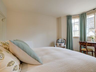 A bedroom with a bed a chair and a desk near windows with curtains at The Old Dairy in Shilton