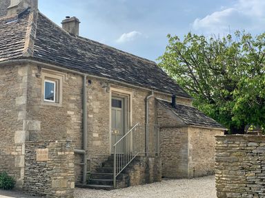 Stone house with slate roof a door with steps and railing and a tree in the background at The Old Dairy in Shilton