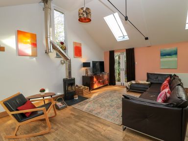 A living room with a sofa, coffee table, and television at The Linhay in Little Coxwell near Faringdon