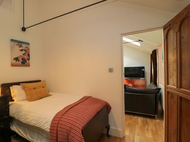 A bedroom with a bed and door leading to a living area at The Linhay in Little Coxwell near Faringdon