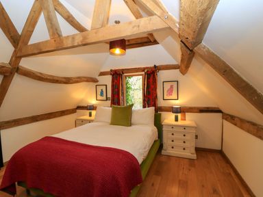A bedroom with a bed, bedside tables, and a window at The Linhay in Little Coxwell near Faringdon