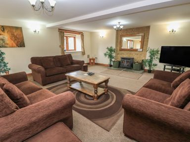 A living room with a fireplace and seating at Tithe Barn, Lyneham