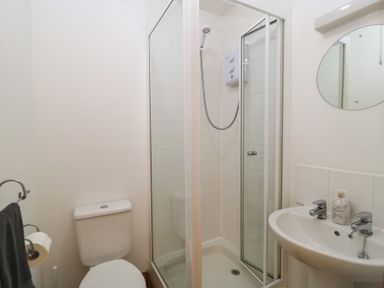 A bathroom featuring a shower, toilet, and wash basin at Tithe Barn, Lyneham