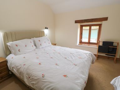 A bedroom with a bed and window at Tithe Barn, Lyneham