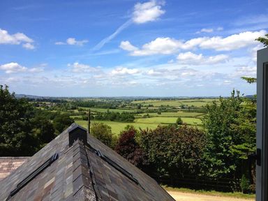 A rural landscape with fields trees and a roof in the foreground at Stepwell in Moreton-In-Marsh