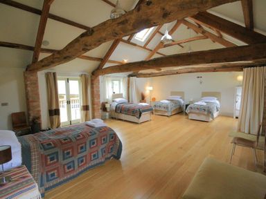 A bedroom with four single beds under exposed wooden beams at Stepwell in Moreton-In-Marsh